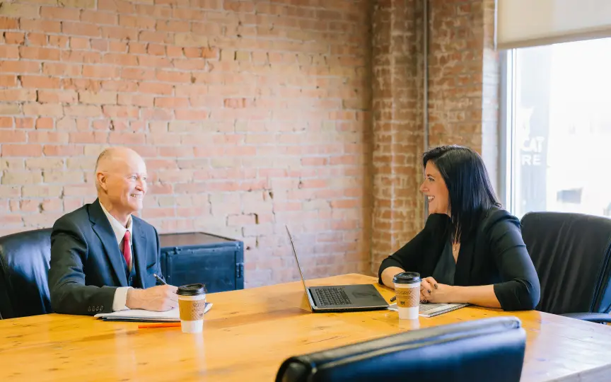 A man and a woman having a pleasant meeting at a conference table in an industrial styled office space